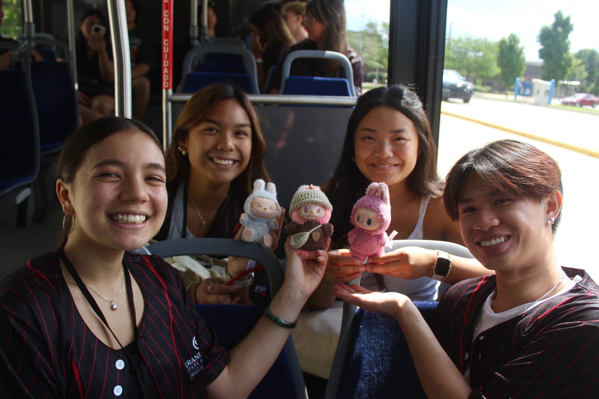 Four students on a Lakerline bus, holding their Labubus.